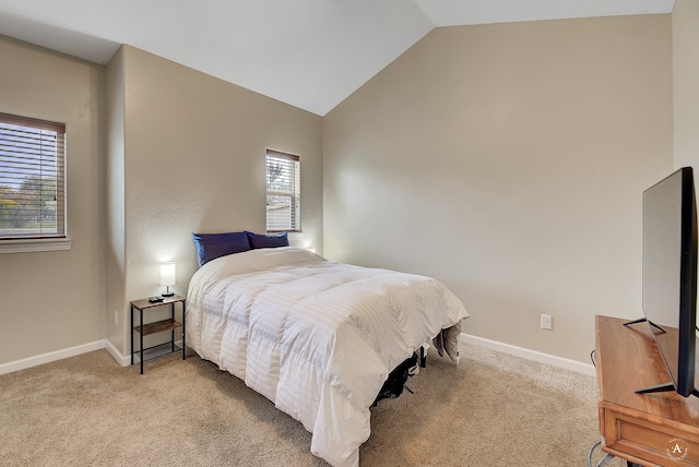 bedroom with vaulted ceiling, multiple windows, and light colored carpet