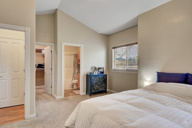 carpeted bedroom featuring a closet, a walk in closet, ensuite bath, and high vaulted ceiling