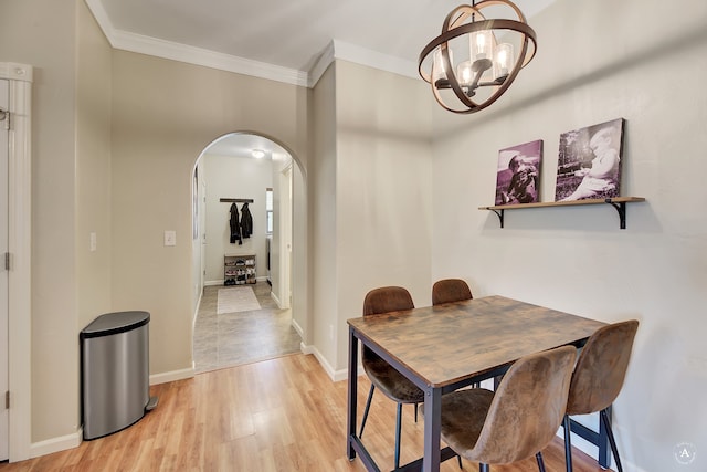 dining space featuring crown molding, light hardwood / wood-style flooring, and an inviting chandelier