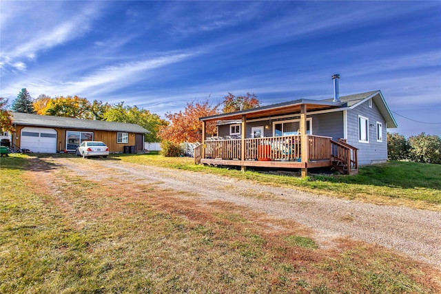 view of front of property featuring an attached garage, a wooden deck, a front lawn, and dirt driveway