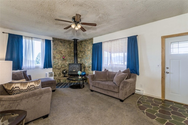carpeted living area with a ceiling fan, baseboard heating, a wood stove, and a textured ceiling
