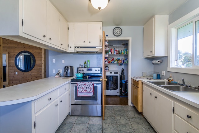 kitchen featuring washer / dryer, white cabinetry, stainless steel electric range oven, wooden walls, and sink