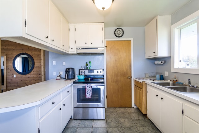 kitchen with wood walls, stainless steel electric range, sink, and white cabinets