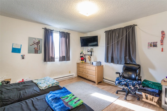 bedroom featuring wood-type flooring, a textured ceiling, and a baseboard heating unit