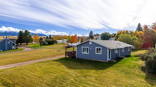 view of side of property with a mountain view and a yard