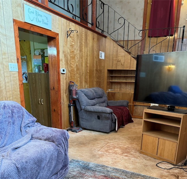 carpeted living room featuring a towering ceiling and wood walls