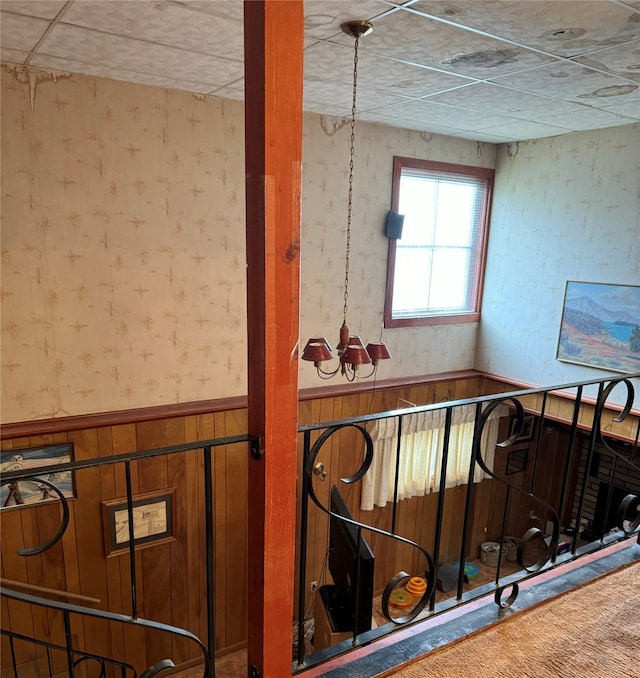 stairs with a chandelier and wood walls