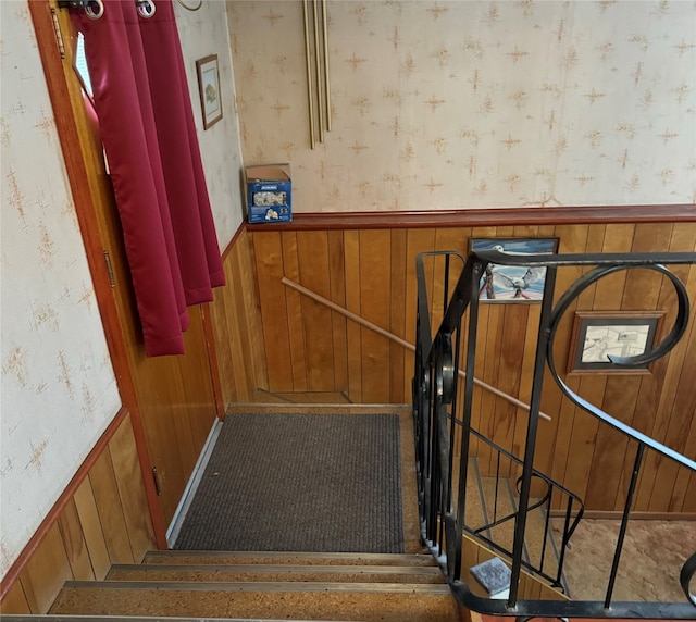 stairway featuring wooden walls