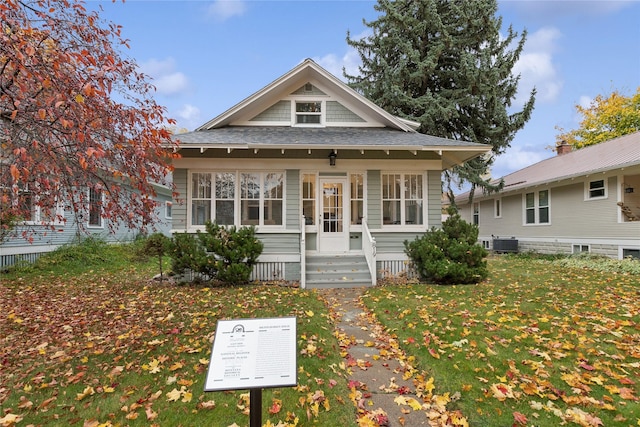 bungalow-style house featuring a shingled roof, central AC, and a front yard