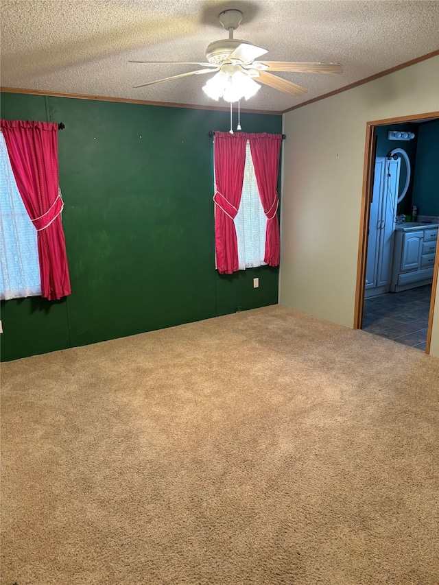 carpeted spare room with ornamental molding, a textured ceiling, and ceiling fan