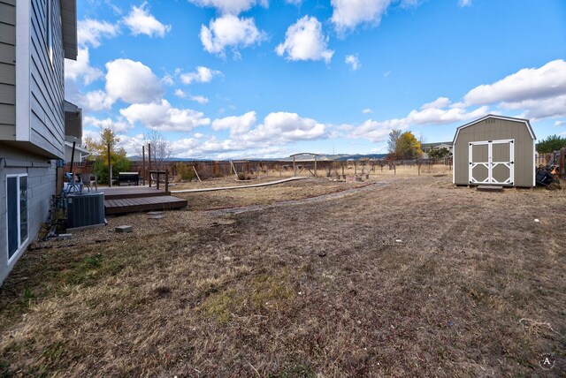 view of yard with a wooden deck, cooling unit, and a storage unit