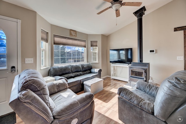 living room featuring light hardwood / wood-style flooring, a wood stove, ceiling fan, and lofted ceiling