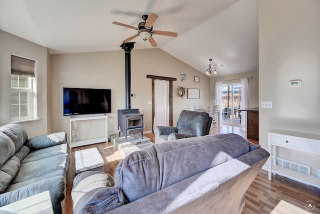 living room with hardwood / wood-style floors, a wood stove, ceiling fan, and lofted ceiling