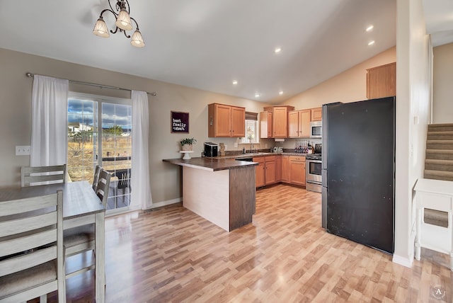 kitchen with lofted ceiling, sink, light wood-type flooring, appliances with stainless steel finishes, and kitchen peninsula