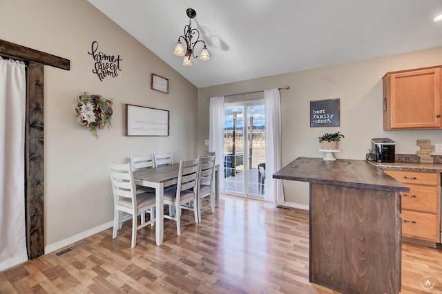 dining room with light hardwood / wood-style floors, an inviting chandelier, and lofted ceiling