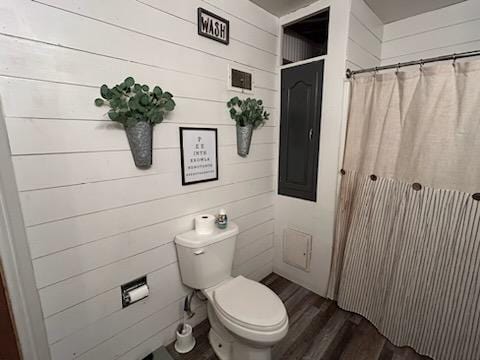 bathroom featuring wooden walls, wood-type flooring, and toilet