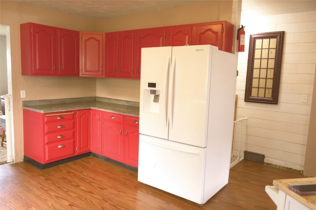 kitchen featuring light hardwood / wood-style floors, a textured ceiling, and white refrigerator with ice dispenser