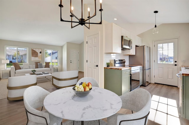 dining space with lofted ceiling and light wood-type flooring