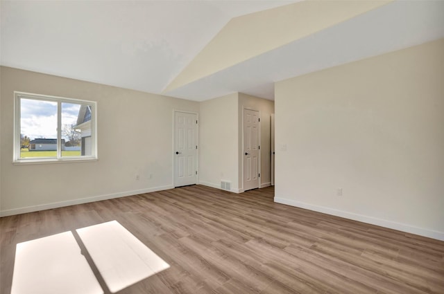 empty room featuring lofted ceiling and light wood-type flooring