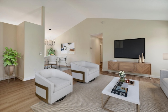 living room with a notable chandelier, light hardwood / wood-style flooring, and vaulted ceiling