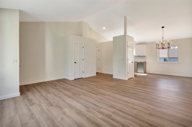 unfurnished living room with lofted ceiling, a chandelier, and light wood-type flooring