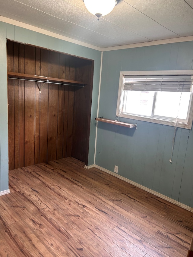 unfurnished bedroom with a closet, wood walls, and hardwood / wood-style flooring