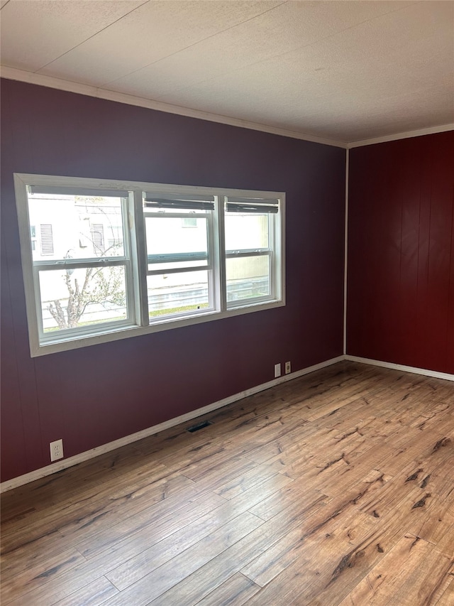 unfurnished room featuring ornamental molding, wooden walls, and wood-type flooring