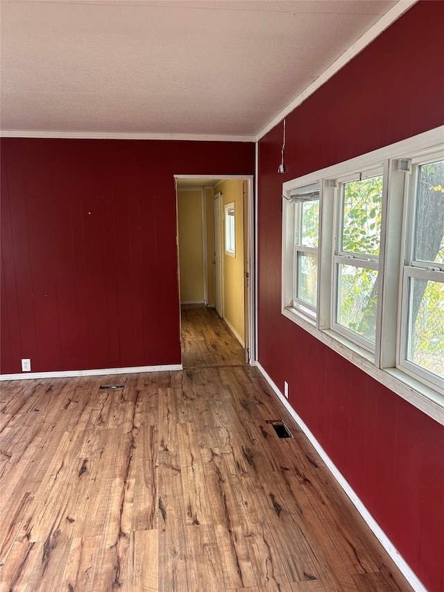 spare room with wood walls, ornamental molding, and hardwood / wood-style floors