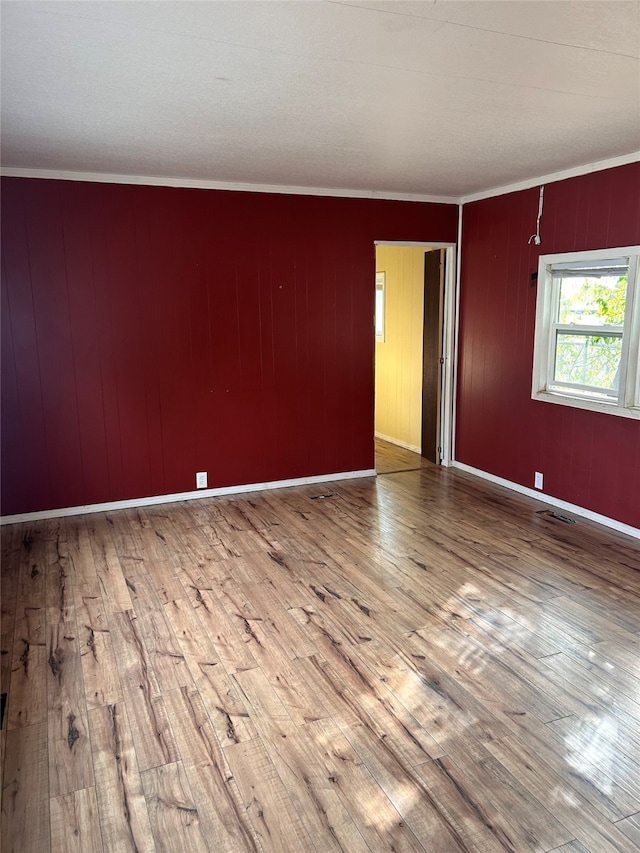 spare room featuring ornamental molding, wood walls, and hardwood / wood-style floors