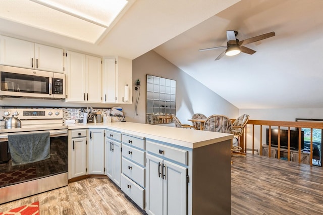 kitchen with white cabinetry, stainless steel appliances, kitchen peninsula, and light hardwood / wood-style flooring