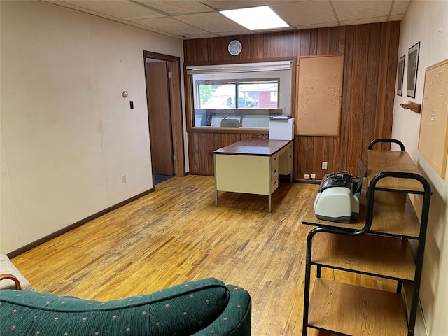 office with a drop ceiling, wood walls, and light wood-type flooring