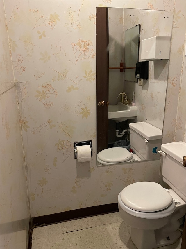 bathroom with toilet, sink, and tile patterned flooring