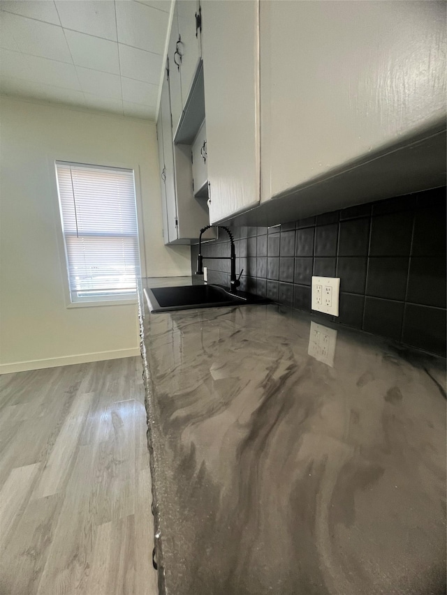 416 2nd St, Deer Lodge, MT 59722 - kitchen with a sink, backsplash, white cabinets, baseboards, and light wood finished floors
