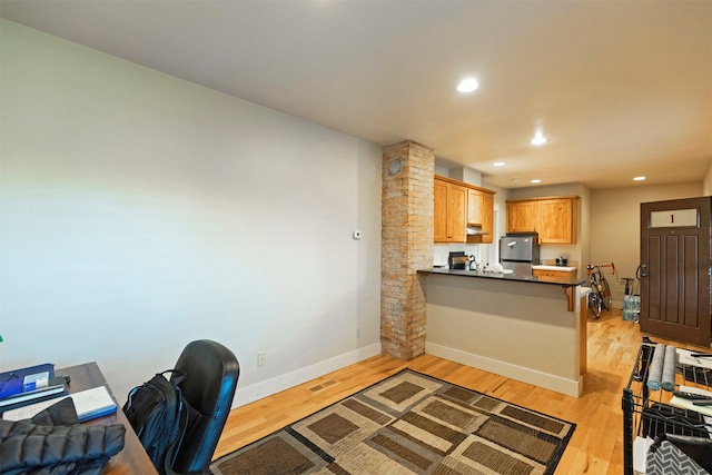 home office with light hardwood / wood-style flooring