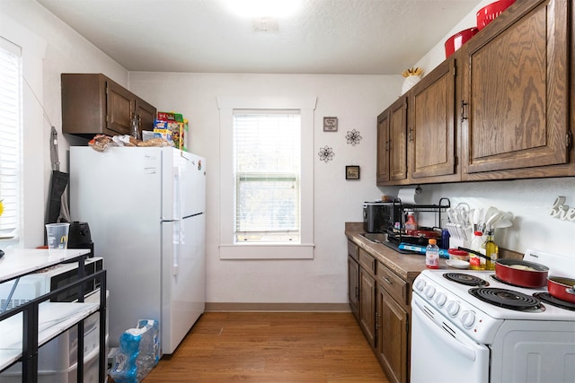 kitchen with hardwood / wood-style floors, a textured ceiling, and white appliances