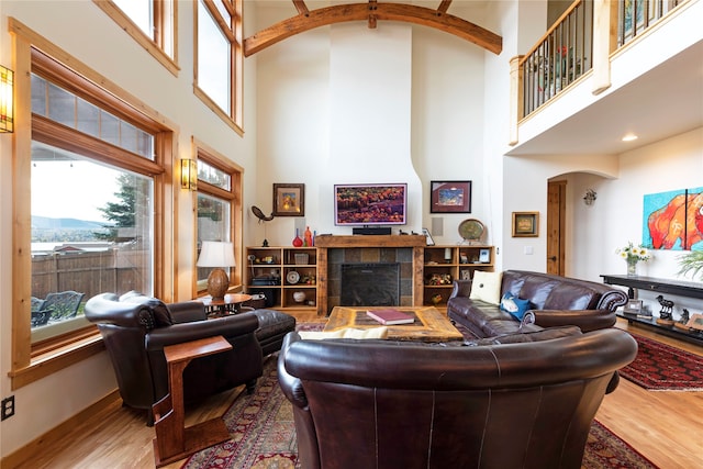 living room with a high ceiling, a fireplace, and light hardwood / wood-style floors