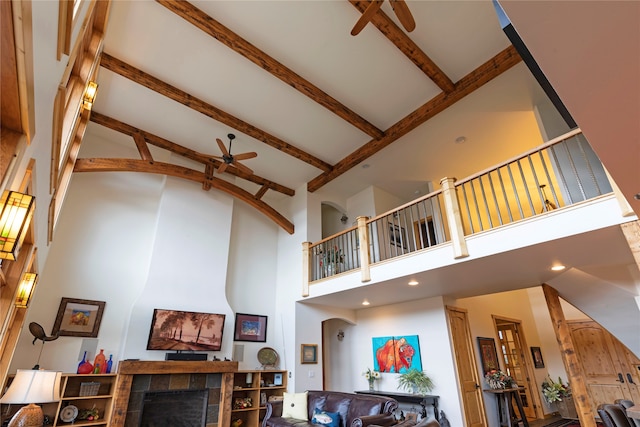 living room featuring beam ceiling, high vaulted ceiling, a fireplace, and ceiling fan