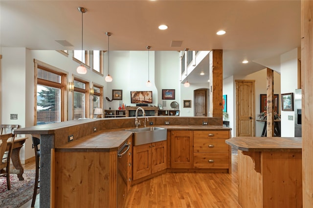 kitchen with light hardwood / wood-style floors, sink, a kitchen breakfast bar, and hanging light fixtures