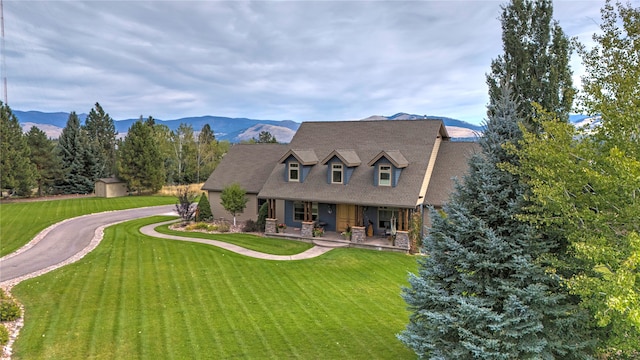 new england style home with a mountain view, a front yard, a patio area, and a storage shed