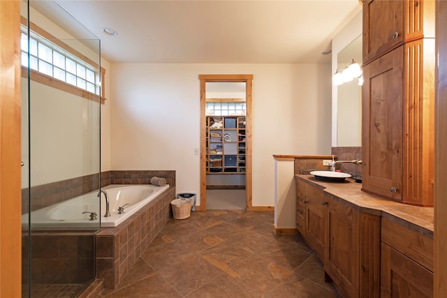 bathroom featuring vanity, a relaxing tiled tub, and tile patterned floors