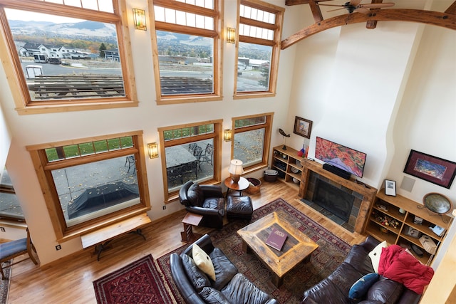 living room featuring a high ceiling, light wood-type flooring, and ceiling fan