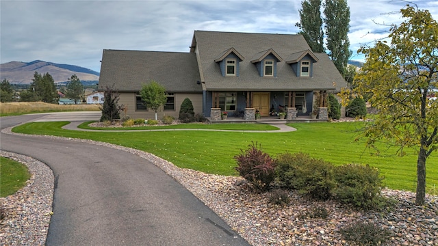 view of front of home with a porch, a mountain view, and a front yard