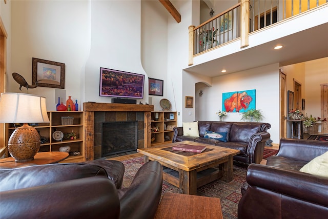 living room featuring beamed ceiling, a tile fireplace, and a towering ceiling