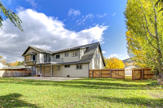 rear view of house with a balcony, a yard, and a patio