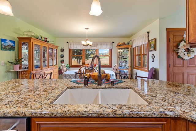 kitchen featuring a chandelier, sink, light stone countertops, and pendant lighting