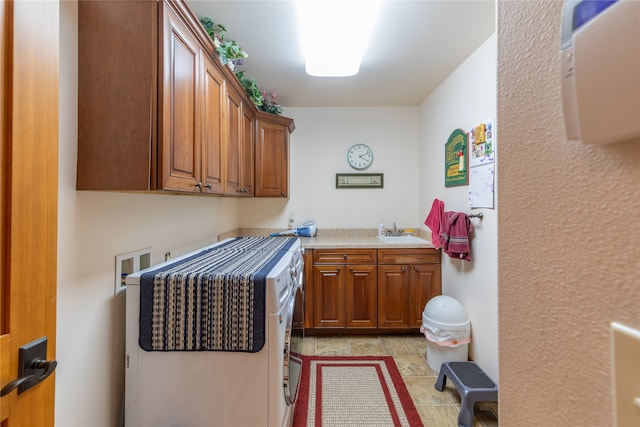 washroom featuring sink, light tile patterned floors, washer hookup, and cabinets