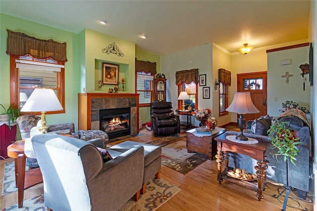 living room featuring a tiled fireplace, light wood-type flooring, and plenty of natural light