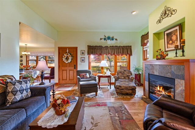 living room with a chandelier, a tile fireplace, and light wood-type flooring