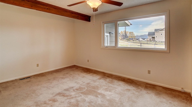 carpeted spare room with beam ceiling, a textured ceiling, and ceiling fan