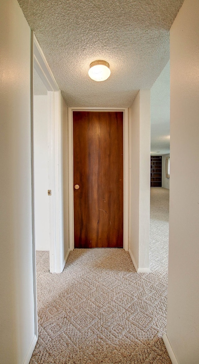 corridor featuring a textured ceiling and light colored carpet